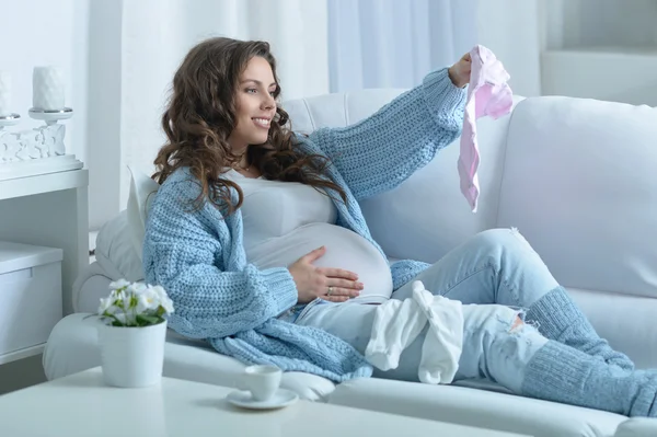 Gravid kvinna med babykläder — Stockfoto