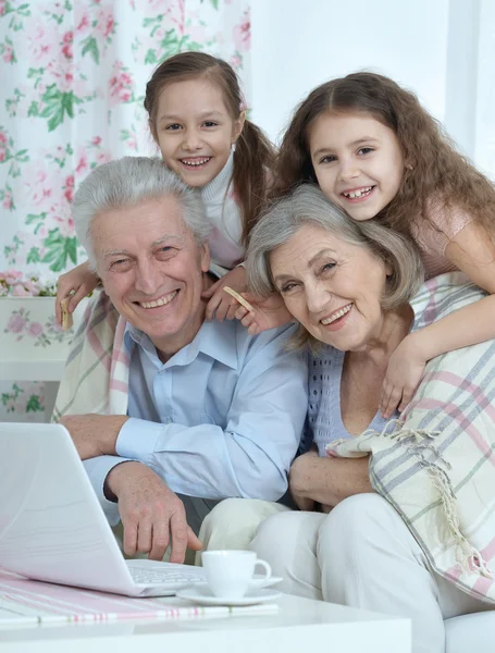 Starší pár s vnoučaty a laptop — Stock fotografie