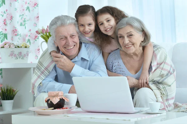 Pareja de ancianos con nietos y portátil —  Fotos de Stock