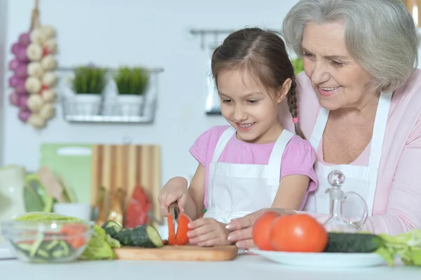 Äldre kvinna med barnbarn matlagning — Stockfoto