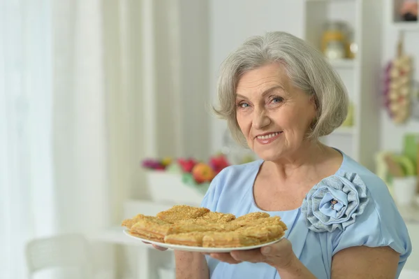 Äldre kvinna med välsmakande paj — Stockfoto