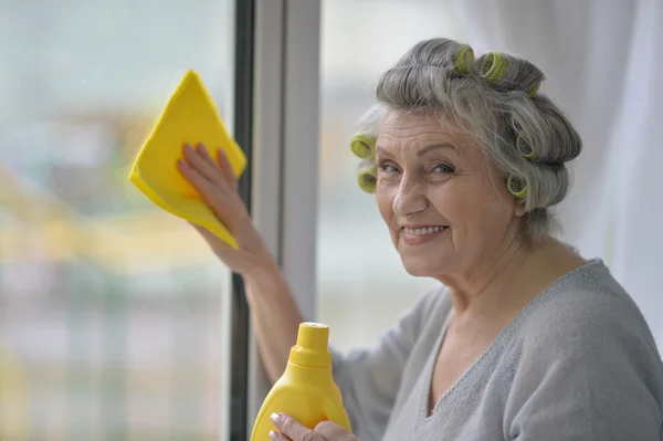 Старшая женщина уборка окна — стоковое фото