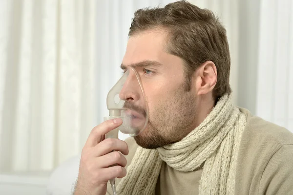 Uomo che inspira attraverso la maschera dell'inalatore — Foto Stock