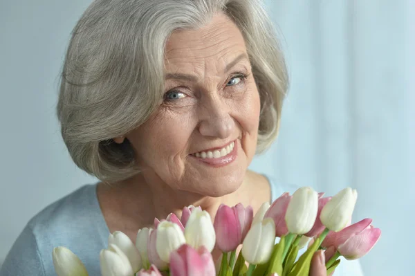 Mulher sênior com flores florescendo — Fotografia de Stock