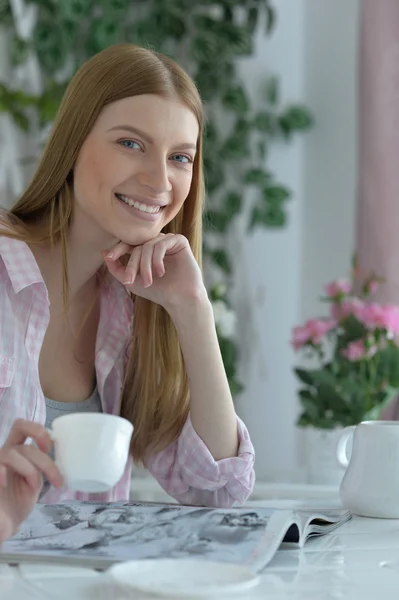 Женщина пьет чай в кафе и читает журнал — стоковое фото