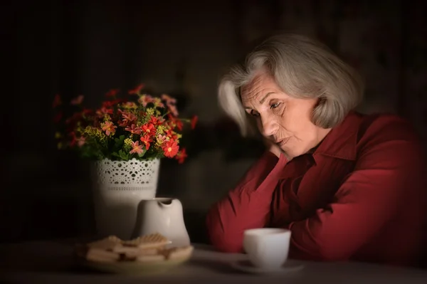 Portrait of an old woman sitting in the evening at home — Stock Photo, Image