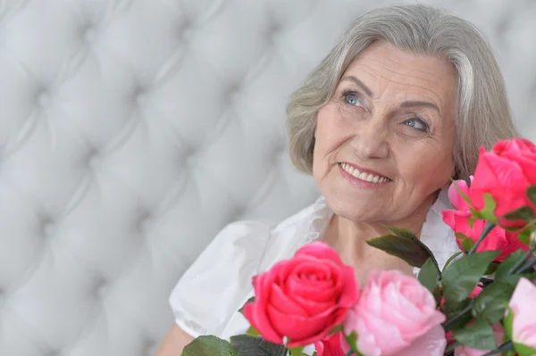 Mujer mayor con flores en flor — Foto de Stock