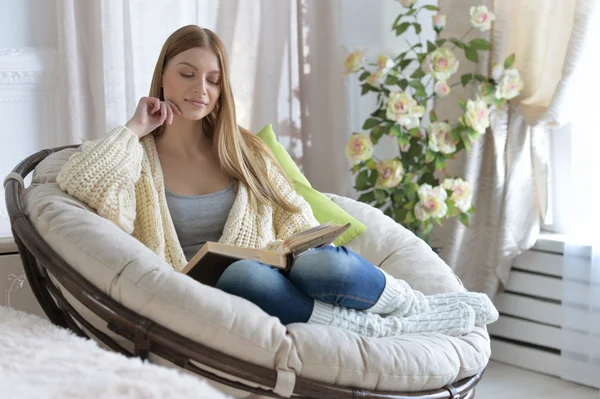 Woman reading a book in cozy armchair — Stock Photo, Image