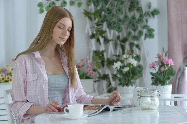Жінка п'є чай в кафе і читає журнал — стокове фото