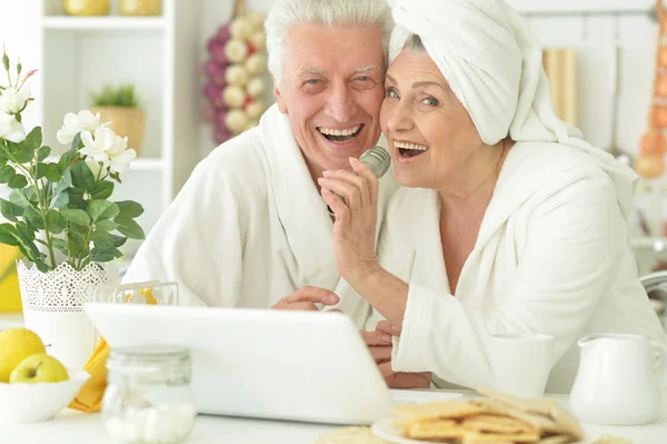 Senior paar in een badjassen met laptop — Stockfoto