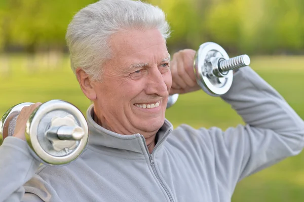 Elderly man exercising with dumbbells — Stock Photo, Image