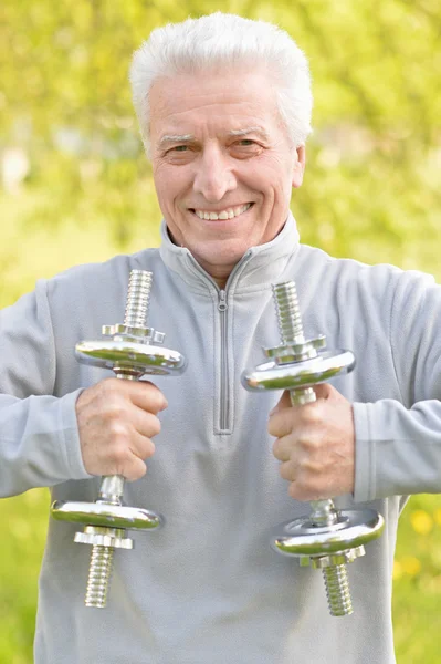 Elderly man exercising with dumbbells — Stock Photo, Image