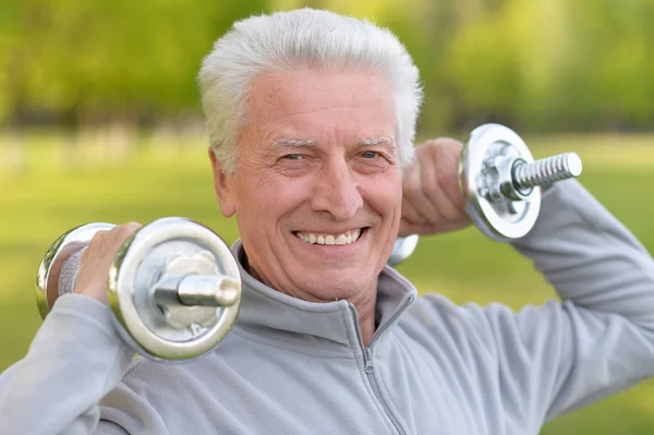 Elderly man exercising with dumbbells — Stock Photo, Image