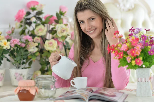 Женщина пьет чай с журналом — стоковое фото