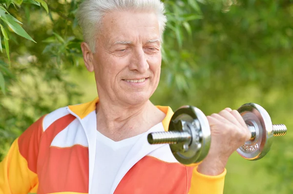 Elderly man exercising with dumbbell — Stock Photo, Image