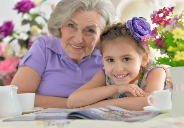 Old woman with a young girl drinking tea — Stock Photo, Image