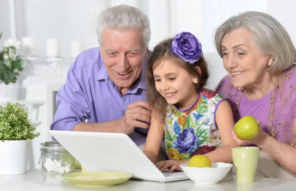 Grootouders en meisje met laptop — Stockfoto