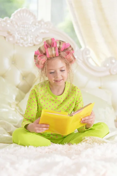 Маленькая девочка в бигуди с книгой — стоковое фото