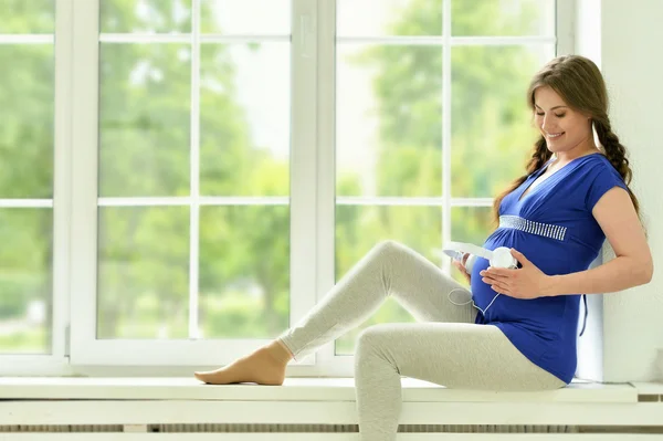 ヘッドフォンで家で妊娠中の女性 — ストック写真