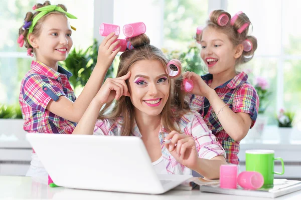 Niñas y madre en rulos de pelo con ordenador portátil — Foto de Stock