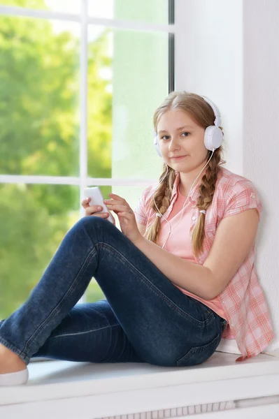 Jeune fille dans les écouteurs avec smartphone — Photo