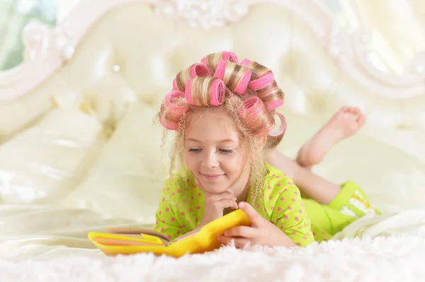 Niña en rizadores de pelo con libro — Foto de Stock