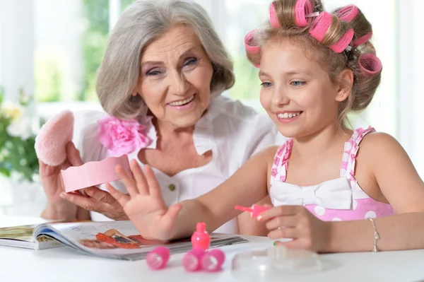 Маленька дівчинка з бабусею з журналом і лаком для нігтів — стокове фото