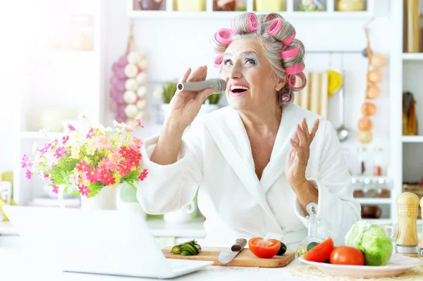 Mulher sênior em rolos de cabelo na cozinha — Fotografia de Stock