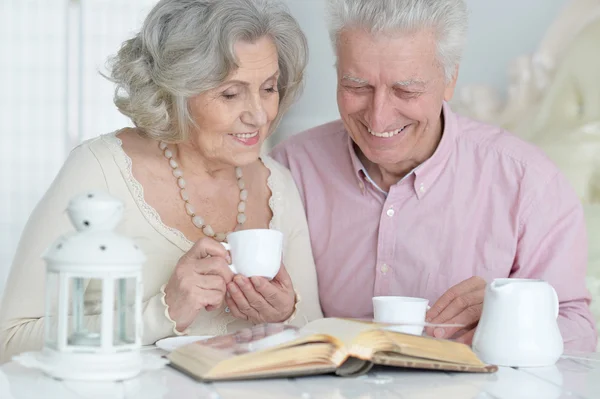 Pareja mayor bebiendo té con libro — Foto de Stock