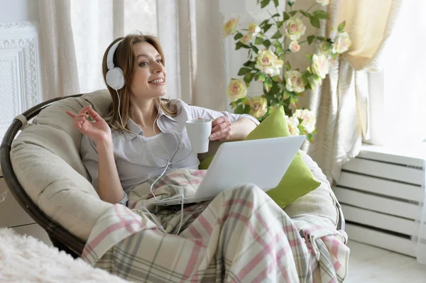 Mujer joven en auriculares con portátil — Foto de Stock