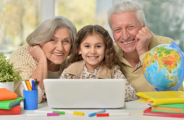 Far-och morföräldrar och liten flicka med laptop — Stockfoto