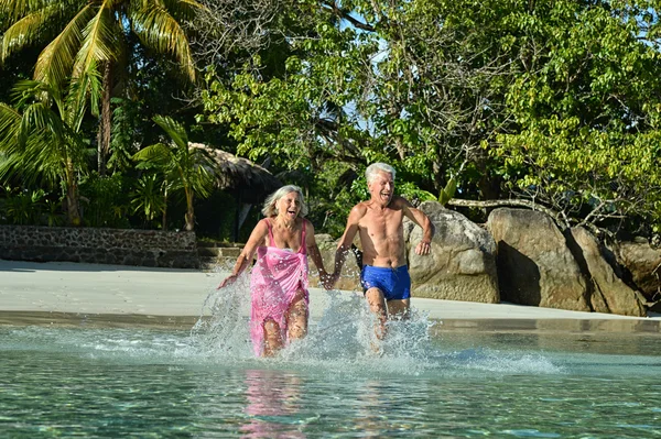 Pareja mayor corriendo en la playa — Foto de Stock