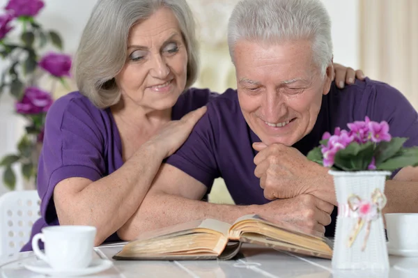 Casal sênior com livro beber chá — Fotografia de Stock