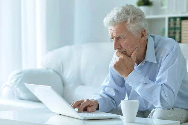 Hombre mayor en casa con el ordenador portátil — Foto de Stock