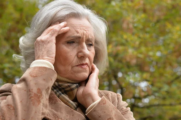 在公园里头疼的悲伤的老年妇女 — 图库照片