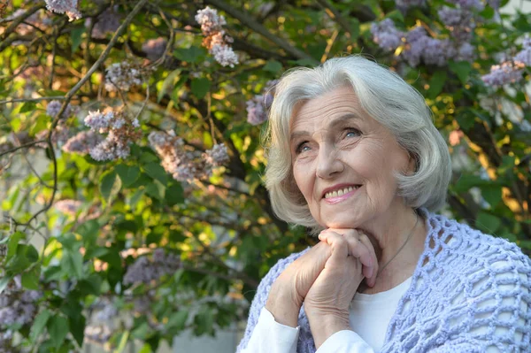 在公园里由紫丁香组成的漂亮的老年快乐女人 — 图库照片