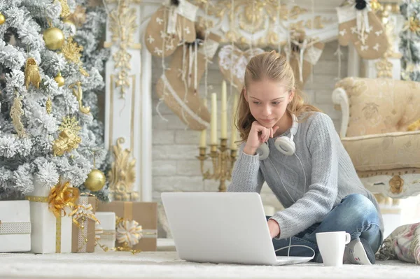Dizüstü Bilgisayarı Olan Güzel Bir Kız Noel Ağacının Yanında Oturuyor — Stok fotoğraf