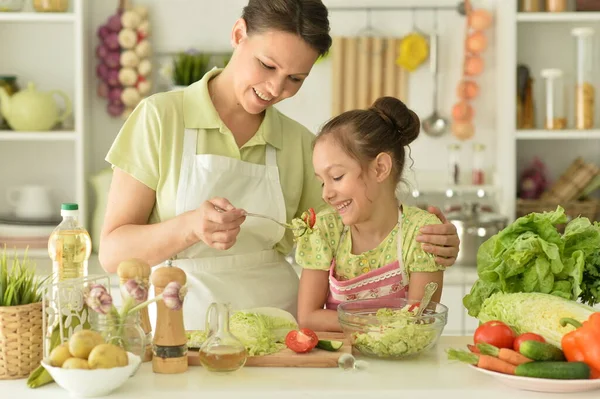 可愛いです女の子とともに彼女のお母さん料理とともにキッチンテーブル — ストック写真