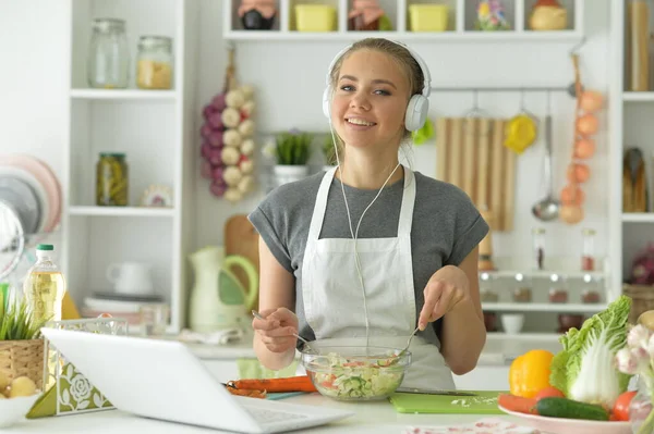 キッチンでサラダを作って音楽を聴くかわいい女の子 — ストック写真