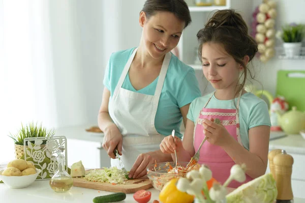 可愛いです女の子とともに彼女のお母さん料理とともにキッチンテーブル — ストック写真