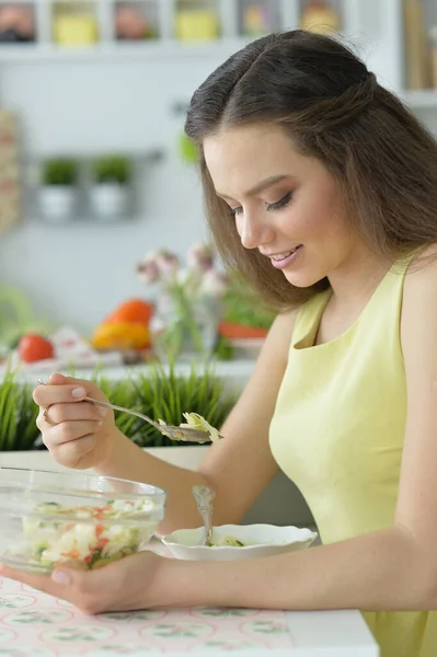 美しい若い女性が台所でサラダを食べる — ストック写真