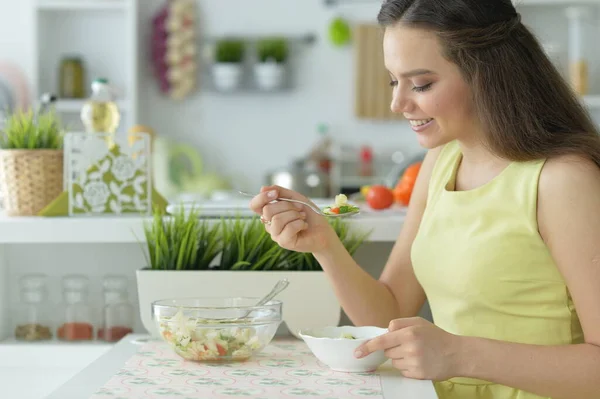 美しい若い女性が台所でサラダを食べる — ストック写真