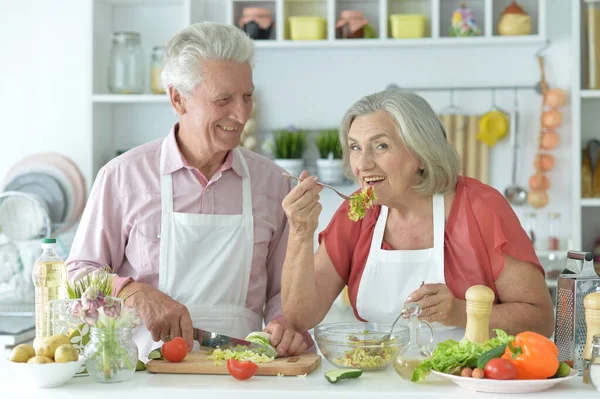 快乐的老夫妇在厨房一起做沙拉 图库照片