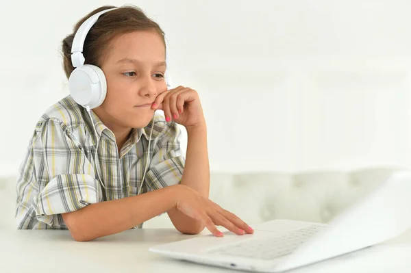 Schattig Meisje Hoofdtelefoon Met Behulp Van Laptop Thuis Aan Balie — Stockfoto