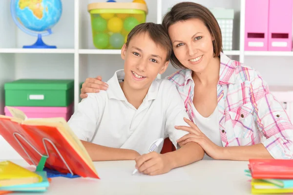 息子と一緒に家で宿題をしている母親は — ストック写真