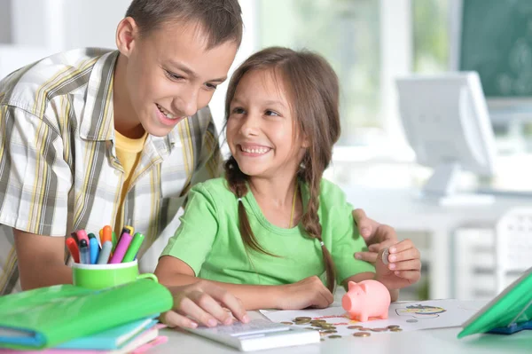 Bonito Menino Menina Colocando Moedas Mealheiro Enquanto Sentado Mesa — Fotografia de Stock