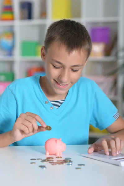 Cute Boy Pitting Coins Piggy Bank While Sitting Table — Stock Photo, Image