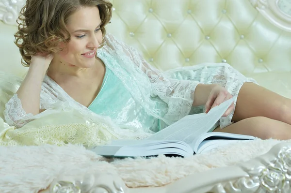 年轻美丽的女人在床上看书 — 图库照片