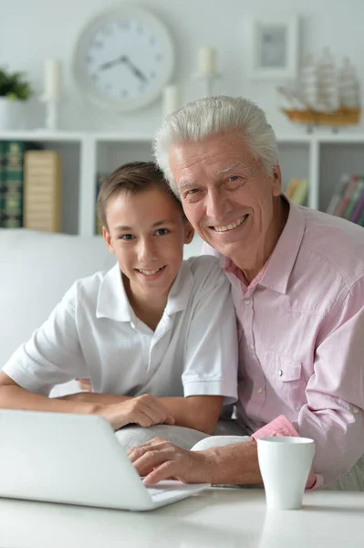男孩和祖父在家里带着笔记本电脑的肖像 — 图库照片