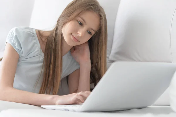 かわいい女の子は家でソファにノートパソコンで横たわっ — ストック写真